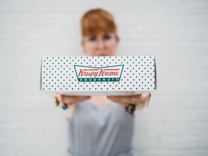 woman holding Krispy Kreme donuts box